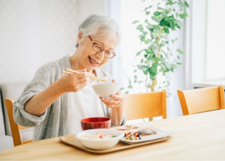 女性の高齢者が楽しそうにご飯を食べる様子